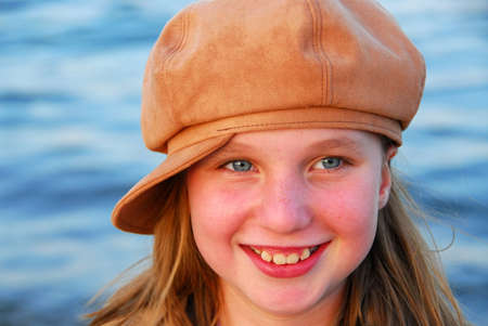 Cute preteen girl in a brown hat on blue water backroundの写真素材
