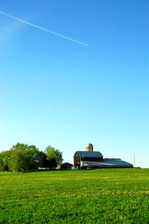 Farmhouse and barn among green fields, verticalの写真素材