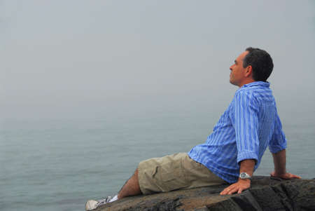 Man looking at the foggy ocean. Uncertain future concept.の写真素材
