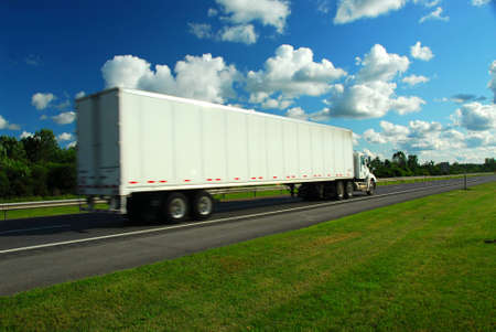 Fast moving eighteen wheeler on a highway, truck is a bit blurred because of speed