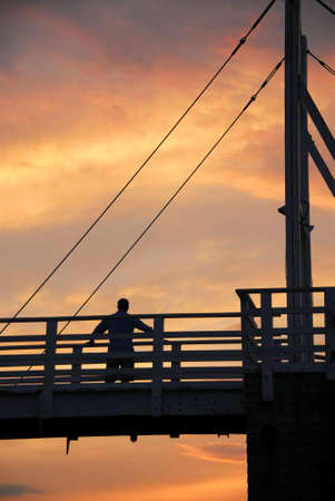Man watching sunset on a footbridge in Perkins Cove, Maineの写真素材