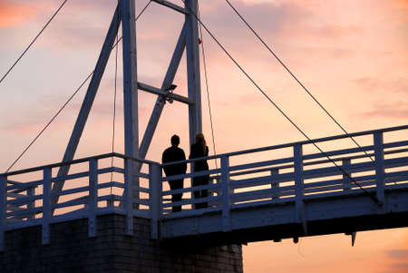 Couple watching sunset on a footbridge in Perkins Cove, Maineの写真素材