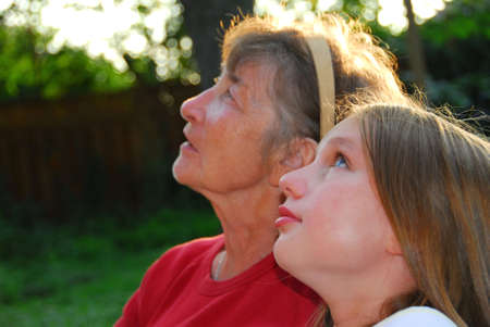 Portrait of a grandmother and granddaughter looking up with hope
