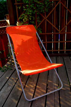 Bright oragne lawn chair on a deckの写真素材