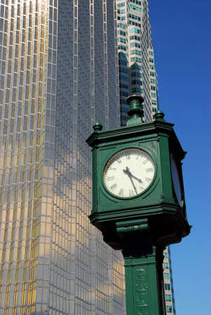 Old public clock with tall modern skyscraper in the backgroundの写真素材