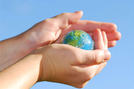 Child holding a globe in hands on blue backgroundの写真素材