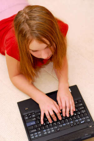 Young girl lying on the floor with portable computerの写真素材