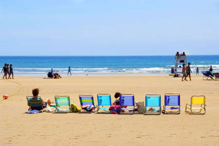 A row of colorful folding chairs on a sandy beachの写真素材