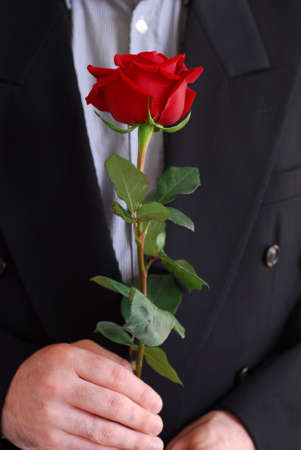 Man in black suit holding a red roseの写真素材