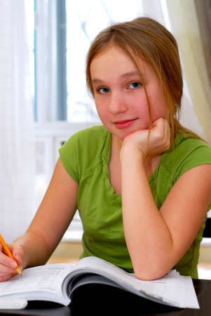 Young school girl doing homework at her desk