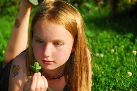Young girl lying on green grass outside holding a green plantの写真素材