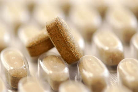 Herbal pills and package of herbal supplement close up