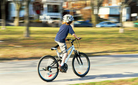 Panning shot of a boy riding a bicycle, motion blurred backgroundの写真素材
