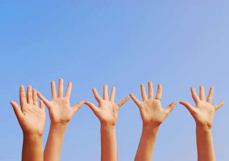 Raised hands on blue sky background with copy space