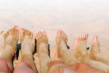 Row of children's feet on a beach covered in sandの写真素材