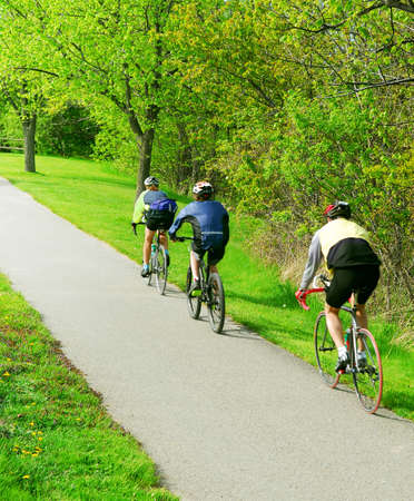 Group of friends bicycling in a summer parkの写真素材