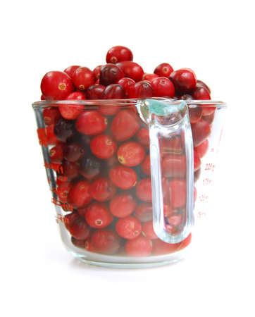 Fresh red cranberries in a glass measuring cup on white backgroundの写真素材