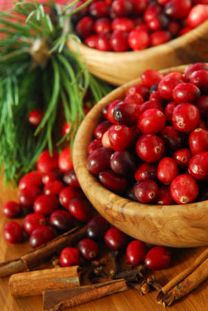 Fresh red cranberries in wooden bowls with spices and pine branches