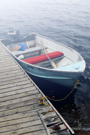 Empty old boat at a dock on a misty lake