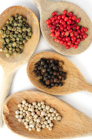 Four kinds of peppercorns in wooden cooking spoons