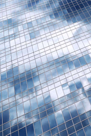 Reflection of a cloudy sky in glass wall of an office buildingの写真素材