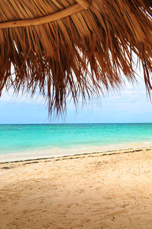 View from under palm leaves shelter onto tropical beach of a Caribbean islandの写真素材