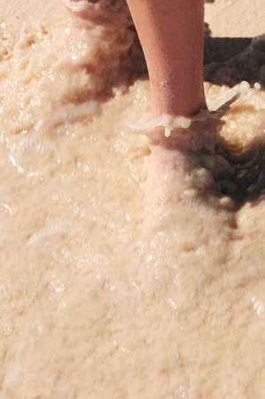 Feet washed in surf on tropical sandy beachの写真素材