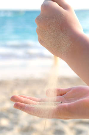 Hands pouring fine sand on a beachの写真素材