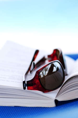 Sunglasses and open book on beach chair - summer vacation conceptの写真素材