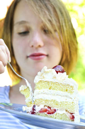 Teenage girl eating a piece of strawberry cakeの写真素材