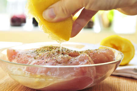 Marinating raw chicken breasts in lemon juice and herbsの写真素材