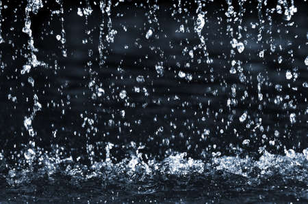 Falling water drops on dark background close upの写真素材