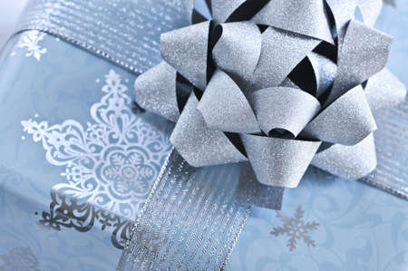 Christmas gift box wrapped in blue paper with silver ribbon close up
