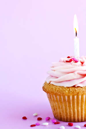 Single cupcake with icing sprinkles and candleの写真素材