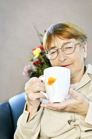 Elderly woman sitting and relaxing with cup of tea