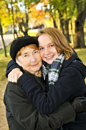 Teen granddaughter hugging grandmother in autumn parkの写真素材