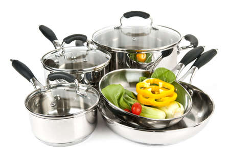 Stainless steel pots and pans isolated on white background with vegetables Stainless steel pots and pans isolated on white background with vegetables