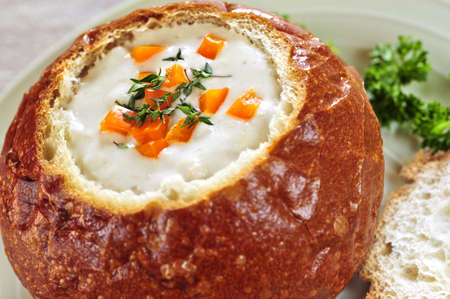 Lunch of soup served in baked round bread bowl