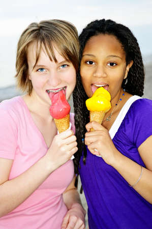 Portrait of two teenage girls eating ice cream conesの写真素材