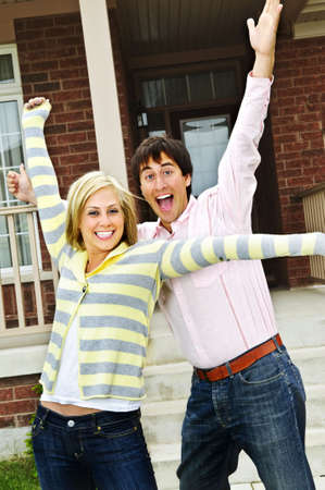 Young excited couple celebrating in front of homeの写真素材