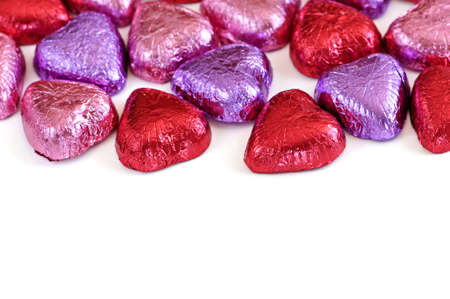 Valentine's chocolates wrapped in red and purple foil on white background