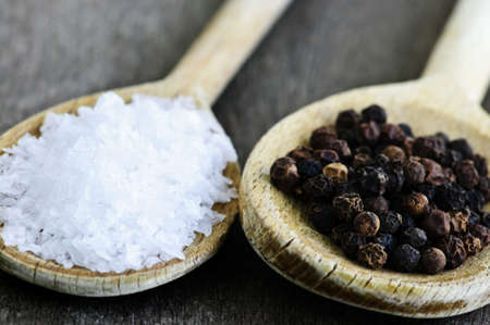 Sea salt and whole peppercorns on wooden spoonsの写真素材