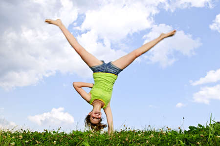 Young teenage girl doing cartwheel in a summer meadowの写真素材