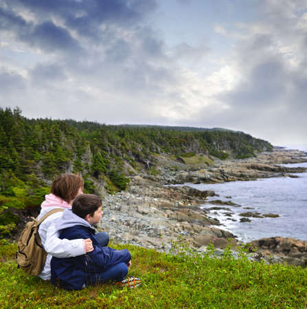 Children looking at coastal view of rocky Atlantic shore in Newfoundland, Canadaの写真素材