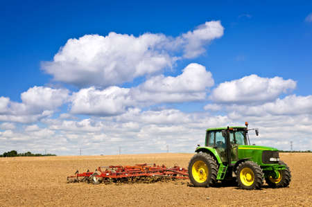 Small scale farming with tractor and plow in field