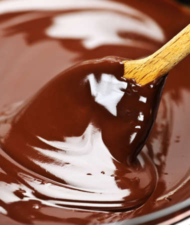 Wooden spoon stirring soft melted rich chocolate