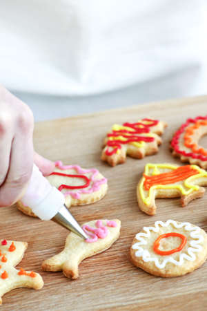 Decorating homemade shortbread cookies with icing from piping bagの写真素材