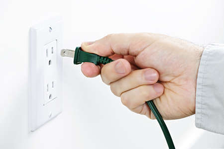 Hand inserting green electrical plug into outlet