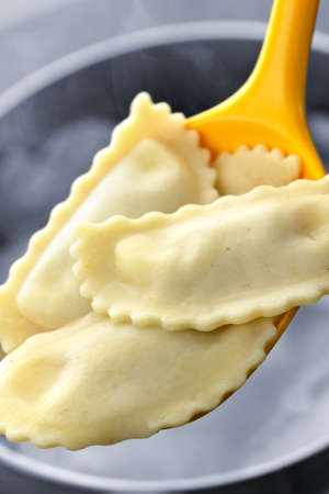 Cooked ravioli lifted from pot on spoonの写真素材