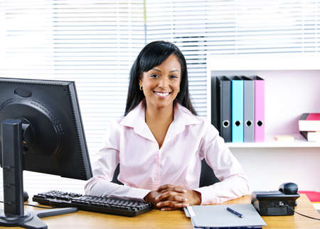 Portrait of smiling young black business woman at desk in officeの写真素材